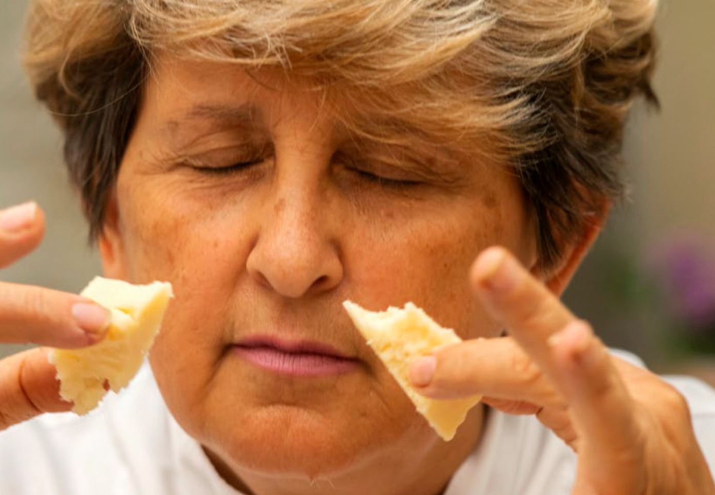 A woman with her eyes closed as she tastes aged cheese — desire formed in the senses, before any decision is made.